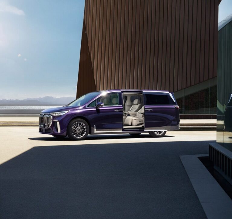 Violetinis Voyah Dream su atviromis slankiomosiomis durimis šiuolaikinio architekturinio pastato fone